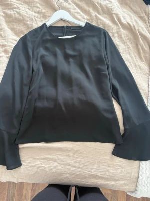 Svart blus med vida ärmar - Stilren svart blus i tunnt skönt material. Passar xs-m. Supersnygg och skön till vår och sommar men även med en jacka på hösten. Säljer då den tyvärr inte kommer till användning längre.🥹❣️skriv för bild på eller för att diskutera pris!!!