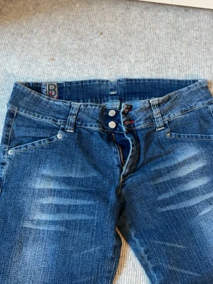Blå lågmidjade jeans - Säljer ett par blå vintage bootcut jeans från Boosley. Står ingen storlek men skulle säga M💕