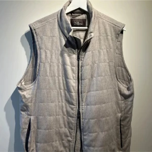 Grå quiltad väst från Oscar Jacobson - Snygg grå quiltad väst från oscar Jacobson med dragkedja framtill. Perfekt för lager-på-lager under kyligare dagar. Västen har en stilren design och är lätt att matcha med olika outfits.