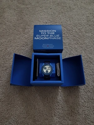 Omega x Swatch MoonSwatch blå - Säljer en Omega x Swatch MoonSwatch Mission to the Super Blue Moonphase. Klockan har blå boett och svart/blått armband, med vit urtavla och tydliga månfaskomplikationer. Levereras i originalbox med tillbehör.