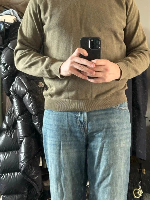 Olivgrön sweatshirt med rund hals - En enkel och stilren olivgrön sweatshirt med rund hals och ribbade muddar vid ärmslut och nederkant. Perfekt för en avslappnad look och lätt att matcha med jeans eller andra byxor. Materialet känns mjukt och bekvämt.