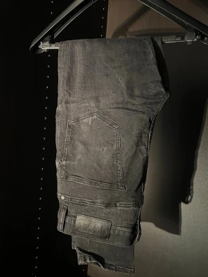 Svarta jeans från diesel  - Säljer ett par svarta skinny jeans från Diesel med slitning på ena benet och klassiska fem fickor. Jeansen har en tvättad look och är tillverkade i bomull med lite stretch för skön passform. Perfekta för en trendig och avslappnad stil.