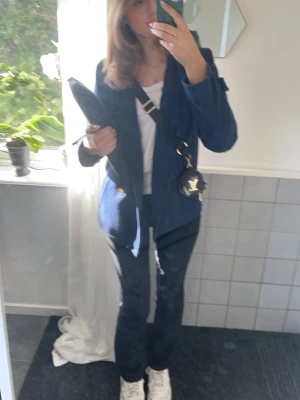 Mörkblå ulljacka med dragkedja - Snygg mörkblå jacka i ullmix med knappar framtill och lång ärm. Jackan har en enkel, stilren design och passar perfekt till vardagsoutfits. Praktisk och bekväm för både höst och vår. Jackan är från Levis och är bra kvalité. Storlek är M men ärmarna är lite kortare så passar som S