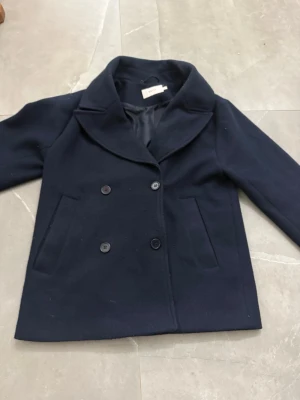 Mörkblå skepparkavaj från ONY  - Säljer en mörkblå kappa från Nelly i storlek M den är knotig men det går bort men maskin 