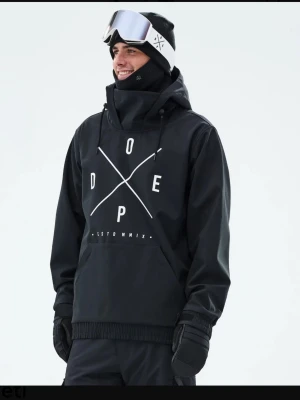 Svart jacka från Dope  - Snygg svart vindjacka från Dope Snow med stor vit logga. Perfekt för dig tex skidåkning. Materialet är vindtätt och vattenavvisande. Det är tjejmodell jag säljer , använd 1 gång