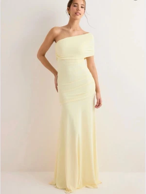 Klänning - Gul långklänning från Nelly med oneshoulder-design och draperade detaljer över byst och rygg. Perfekt som balklänning eller liknande. Helt slutsåld på hemsidan, för egna bilder kan ni gärna höra av er💞