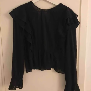  - Fin svart blus från Zara med volanger. Storleken är XL men passar enligt mig allt från en m-xl. Knappt använd, frakt tillkommer!