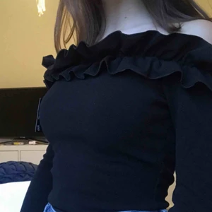  - Helt oanvänd (lapparna kvar) svart off-shoulder tröja med volanger, storlek XS från Nelly. Denna tröja är slutsåld och jag säljer den då den inte kommer komma till användning. Frakt står köparen för, 50kr.