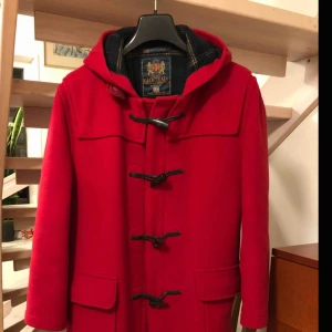  - Fin röd duffel i ull av märket Gloverall. Rymlig modell. Märkt storlek 40 men passar även en 42:a. Är lätt använd men i fint skick. 