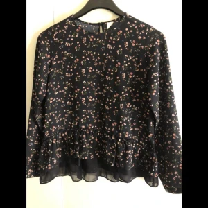 Blommig Blus - En otrolig söt och gullig marinblå blommig blus med lite volanger nedtill. Använd fåtal gånger men märks inte.