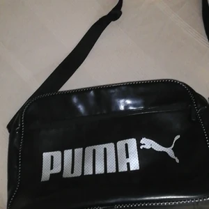Svart läderväska puma - Säljer denna snygga puma väskan pga att den inte kommer till andvändning längre. Den är dock lite sliten i kanterna som man ser på bild 3. Men annars är den i bra skick. Köparen står för frakten på ca 60kr  Den är 39×27 cm. Betalningen sker genom swish.  