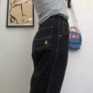 Ascoola svarta byxor i jeansmaterial från Lazy Oaf. Vita synliga sömmar med coolt broderi på baksidan av två smileys. Jag är 179 cm