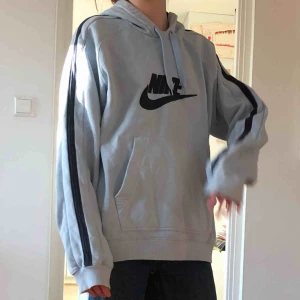  - Ljusblå hoodie från Nike med mörkblått Nike märke och streck på armarna