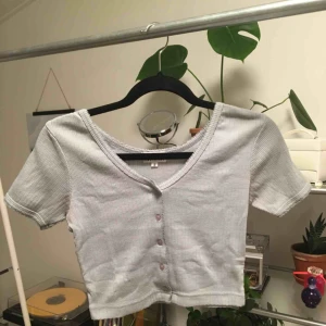  - En jättegullig croptop med knappar. Färgen är ungefär ljusblå/lite grå. Tyget är lite ”räfflat”. Priset inkluderar frakt. <33