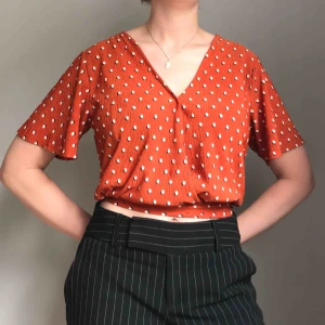  - Frakt ingår! • V-ringad orange topp med svartvita prickar från Bershka • utställda luftiga ärmar och knyts baktill • i storlek M men passar en S lika bra • använd ett fåtal gånger! 