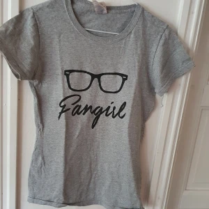 Grå t-shirt med tryck - Grå t-shirt med texten "fangirl" och ett par glasögon över. Fick den i present för några år sen, men ganska säker på att den är från Etsy ⭐ Inte särskilt använd så i bra skick ⭐ Säljs då den inte används. Kontakta vid frågor/intresse 💜 frakt inräknad