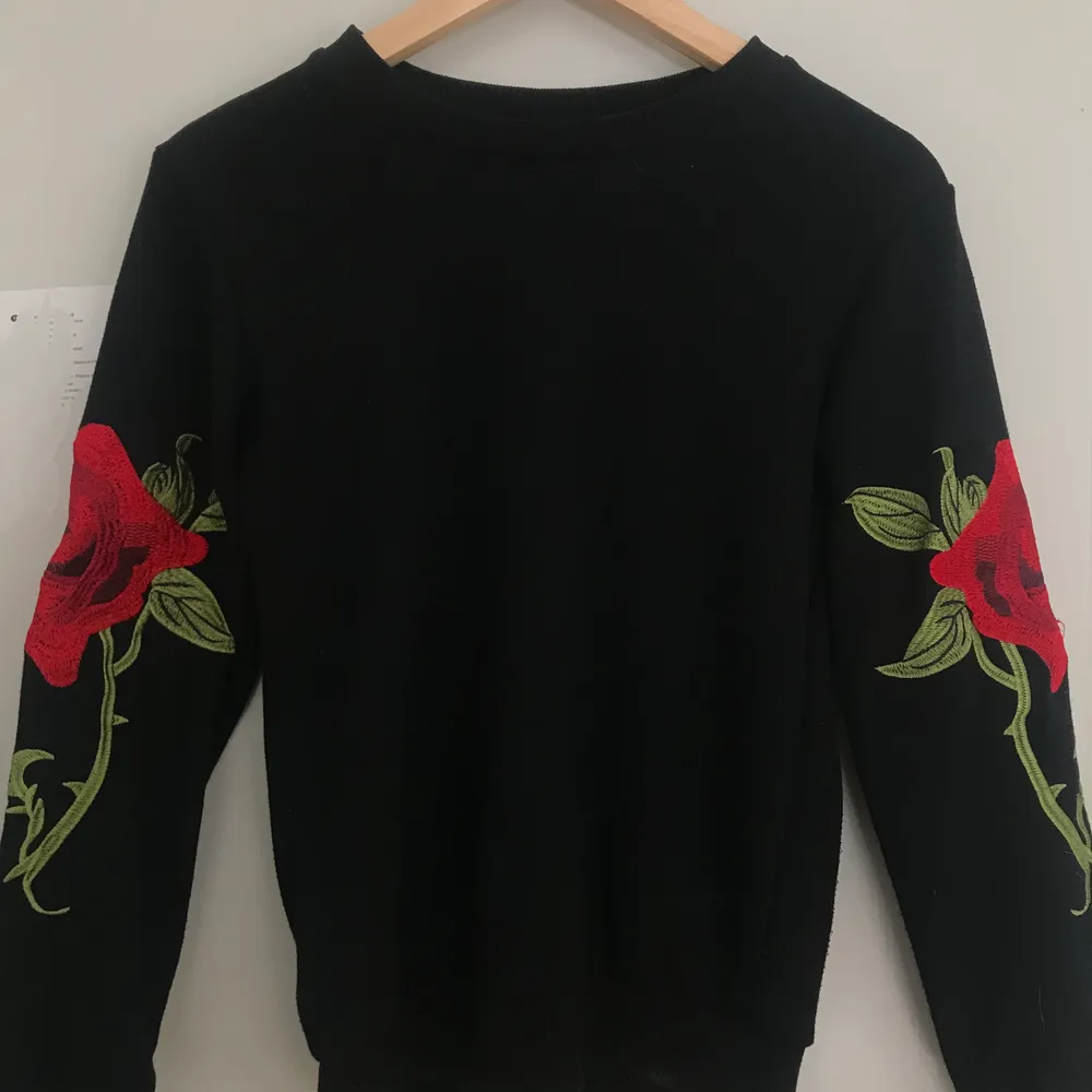 En vanlogt svart sweatshirt med ros detaljer på ärmarna. . Hoodies.