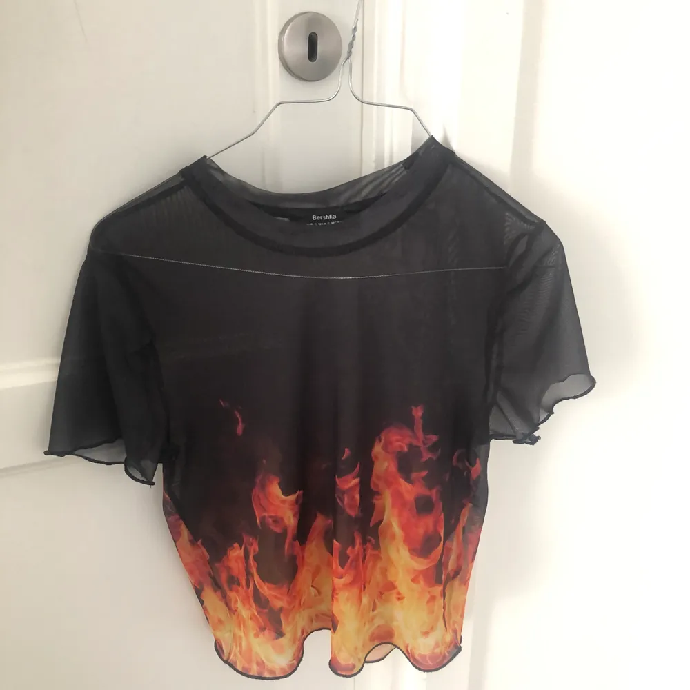 svart mesh T-Shirt från Bershka med eldslågor! storlek S(26) men passar även M. Säljer för att den inte passar min stil :(💘 kontakta mig vid frågor xx. Toppar.