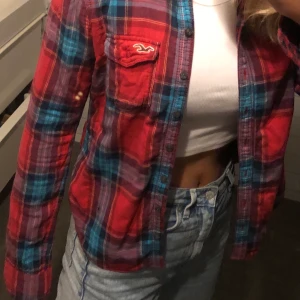 Hollister flanellskjorta - Flanellskjorta i finfint skick från hollister. I rött och blått. Knappt använd och säljer eftersom den är något för liten. Kan mötas i sthlm eller fraktas om köparn betalar:)