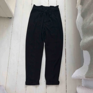  - Svarta lösa högmidjade kostymbyxor från Gina tricot.  Använda 1 gång. Lösa längst ner och längst upp vid låren. Inget stretch material. Två fickor på fram sidan och två fake vid rumpan. Ett snöre som går vid midjan 