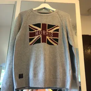 Klassisk Morris pullover med brittisk flaggmotiv. Den är i superfint skick generellt, små hål i armhålorna (som det oftast blir med stickade)