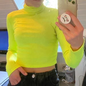 Neongul croppad polo - En neongul polotröja som är något croppad. Sjukt snygg passform och sitter väldigt bekvämt. Har en fläck från färg som jag inte lyckats få bort helt. 