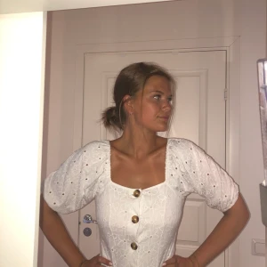 Sommarklänning från Nelly - Vit sommarklänning med träinspirerade knappar & puffärmar. Pris inklusive frakt!