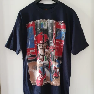 T-shirt med tryck - Mörkblå, eller svart t-shirt (tycker det är svårt att se) med tryck i storlek M. Trycket är rätt "plastigt". Fraktkostnad blir 47kr. Finns kvar!