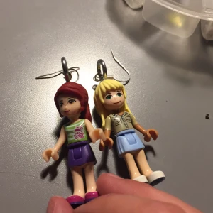 Öronhängen  - Öronhängen med lego gubbar! Kan ej separeras i ben kropp hår eller huvud. Väldigt finna. Kommer i en liten tyg påse med silvriga blommor på😊