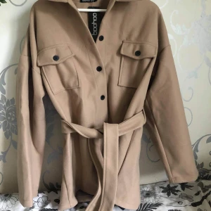 Beige kappa strl 42. - Ny beige kappa med lappar kvar. Storlek 42, 250kr.