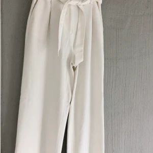 Superfina vita kostymbyxor - Härliga vita kostymbyxor med fin midja och knytband! De är helt raka i passformen vilket jag tycker är supersnyggt + ett fint tjockare material. Använda endast ett fåtal gånger då jag tycker de är lite små för mig. De passar 34/36 beroende på önskad passform. Köparen står för frakt💜