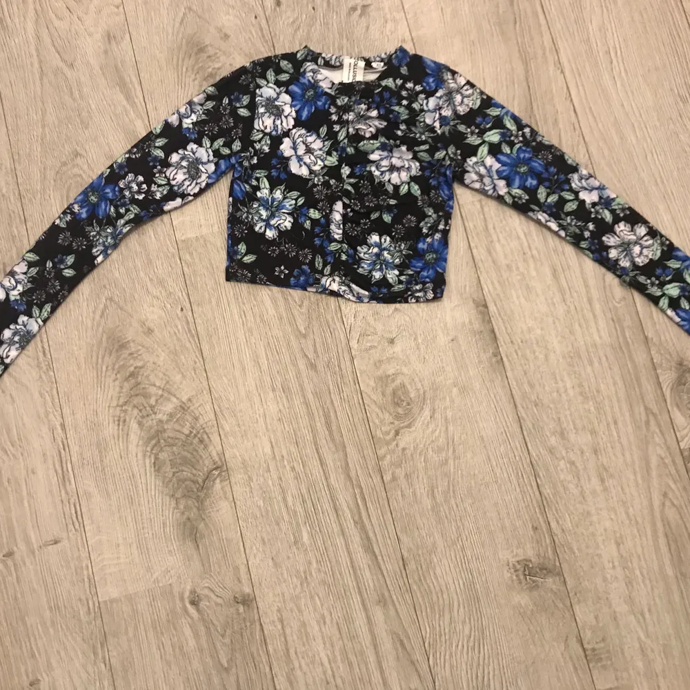 Svart långärmad blommig crop top med vita och blåa blommor. Storlek S. Endast provad. Vid intresse kan eventuellt fler bilder skickas.. Toppar.