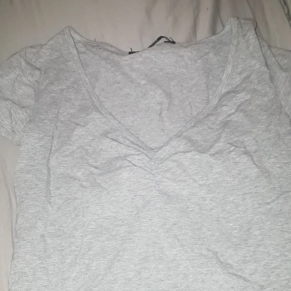 Säljer en helt vanlig grå t-shirt med V ringning och en insyning vid v ringningen. Köparen står för frakten (39kronor). T-shirts.