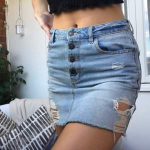 Jeans kjol med slitningar och fyra knappar i fram