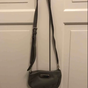  - Jättefin grå liten väska från Marc Jacobs. Inköp i New York för några år sedan, använd väldigt få gånger, i fint skick. Säljer pga använder ej. Fraktar eller möts upp i Stockholm