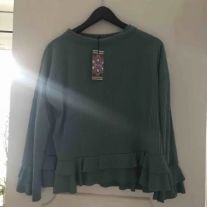  - Blå/grön tröja med volanger. Aldrig använd lapp finns kvar. 