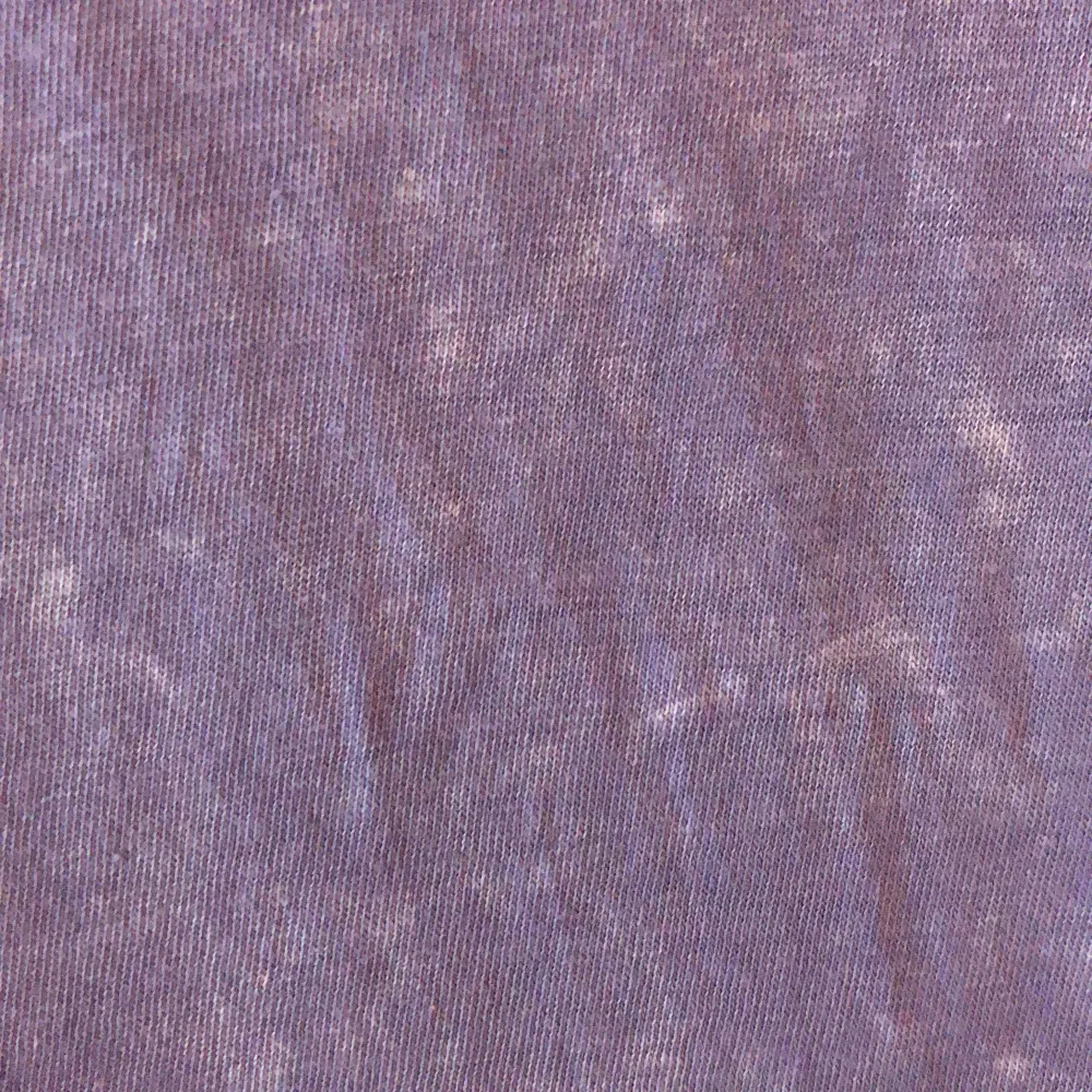 En lila tröja med någon blekt mönster, ser ut som någon sprayat på den med blekningsmedel. Tryck, rätt så stor krage. T-shirts.