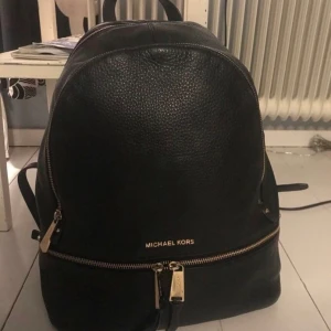 Michael Kors Rhea Backpack Large - Svart läder med gulddetaljer, köpt på Michael Kors butiken i Vancouver (Kanada) för 3700 kr, säljer för 2500 men pris kan diskuteras! Jättefint skick, endast några små repor på dragkedjorna. Får plats med en 13-tums laptop🌸 kan skicka fler bilder!