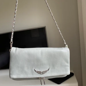 Fin ljusgrå väska från Zadig & Voltaire - Superfin väska från Zadig & Voltaire! Använd ca 5 ggr och är därför i mycket bra skick :) Den enda slitningen jag kunde hitta var lite på dragkedjan(syns på sista bilden). Båda kedjorna ingår + dustbag! Köparen står för frakt, kan annars mötas upp i Lund