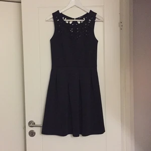  - Svart klänning med dragkedja i ryggen.