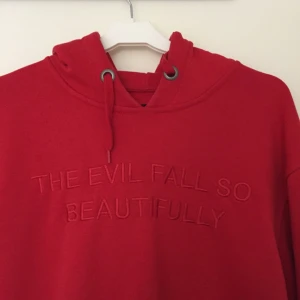  - Röd hoodie från det svenska märket NAND. Broderad text på framsidan: "THE EVIL FALL SO BEAUTIFULLY". Lite oversize fit 