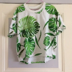  - 🐚 Basic tisha i boxig modell. Tryck med monstreablad - Queen of plants! Storlek Small. Från Weekday MTWTFSS. 100% bomull. Köpt 2hand, bra beg. skick - lite fläckig vid kragen se bild 3! Vid frakt: +45kr 🐚