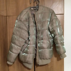  - Vinterjacka från H&M TREND. Knappt använd.  Beige/grå i färgen. Med holografisk effekt.  Möts helst upp vid köp. Med fördel i Uppsala.