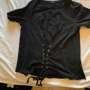  - Svart t-shirt med snörning ner till
