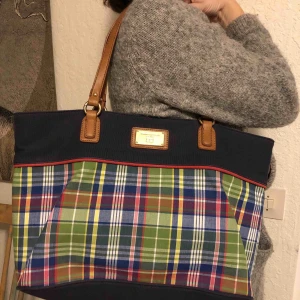 Tommy Hilfiger väska - FLYTTAR SÅ VILL GÄRNA BLI AV MED DEN. Tommy Hilfiger väska i tyg i marinblått och ett färgglatt rutmönster B44xD12xH27 cm. I nyskick. 