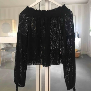  - En off shoulder blus i spets i storlek 36.  Snörning vid ärmarna.  