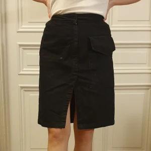 Svart jeanskjol med mittslits - Fin jeanskjol från weekday med en slits framtill. Midjan är lite insydd. 