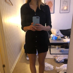 Svart kort klänning  - En svart klänning från zara. Knappar hela vägen samt ett band för att knyta. Storlek XS. 