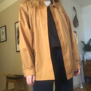 Skjorta/tunn jacka - Skjorta/sommarjacka? i orange/beige. Köptes 2nd hand på Emmaus. Jättefint skick! Köparen står för frakten men kan också mötas upp i centrala Stockholm. Står ingen storlek men sitter over sized på mig som vanligtvis har xs/s! 🤠