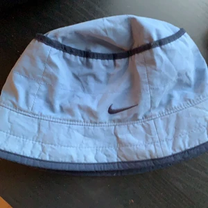 Nike fiskehatt - Fin fiskehatt från nike, köpt från beyond retro. Fint skick men måste varna att den är väldigt liten( detta kommer låta konstigt) så om erat huvud är större än 54 cm så kan det vara lite trångt:)